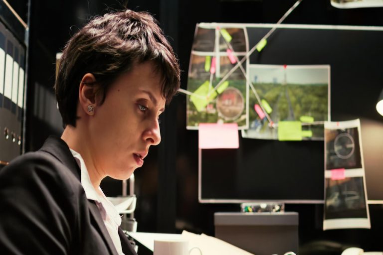 A professional woman in a suit sits at a desk, focused on her laptop. Criminologists play a vital role in crime prevention.